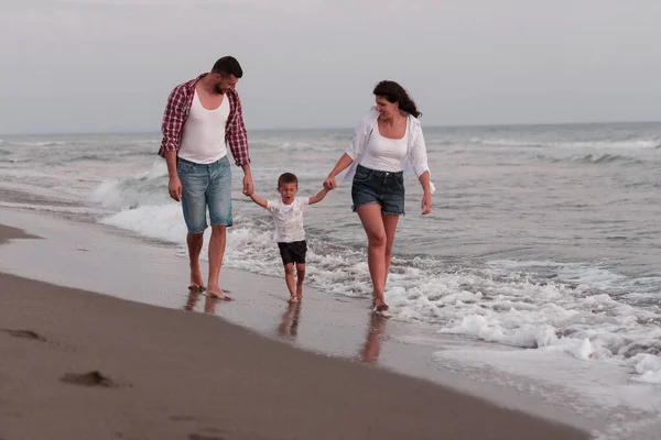 The family enjoys their vacation as they walk the sandy beach with their son. Selective focus — Stok fotoğraf