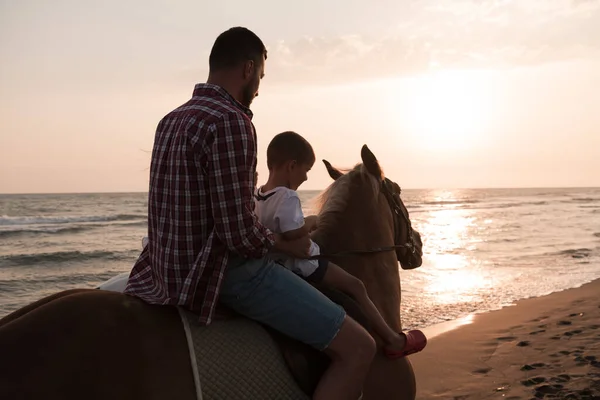 Father and son enjoy riding horses together by the sea. Selective focus — Stok fotoğraf