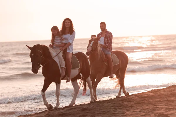 Rodzina spędza czas ze swoimi dziećmi jeżdżąc na koniach razem na piaszczystej plaży. Skupienie selektywne — Zdjęcie stockowe