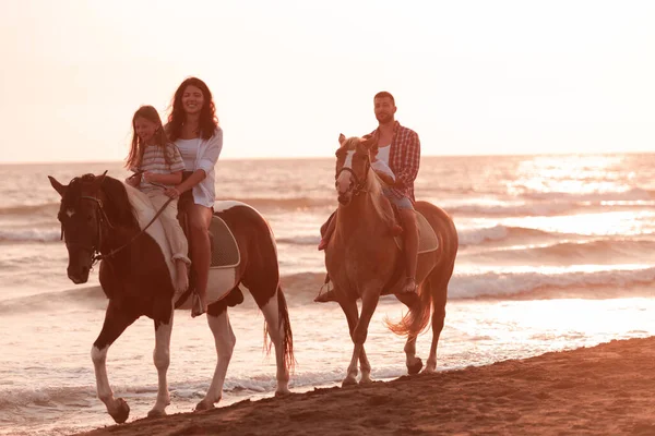 Aile kumlu bir sahilde birlikte ata binerken çocuklarıyla vakit geçirir. Seçici odak 