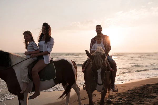The family spends time with their children while riding horses together on a sandy beach. Selective focus — Foto de Stock