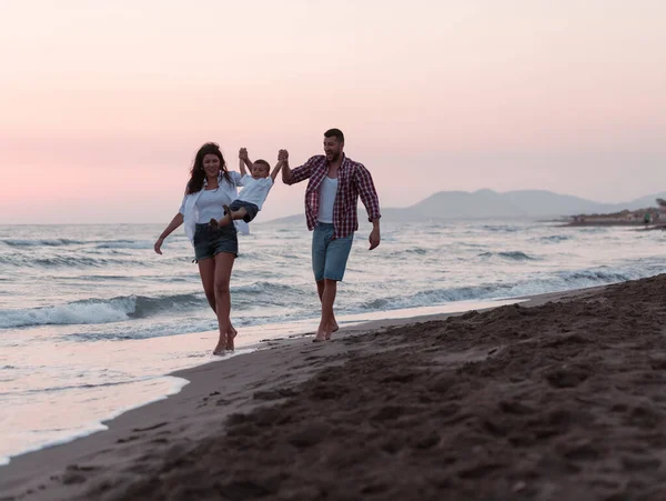 Aile, oğluyla kumsalda yürürken tatilin tadını çıkarıyor. Seçici odak 