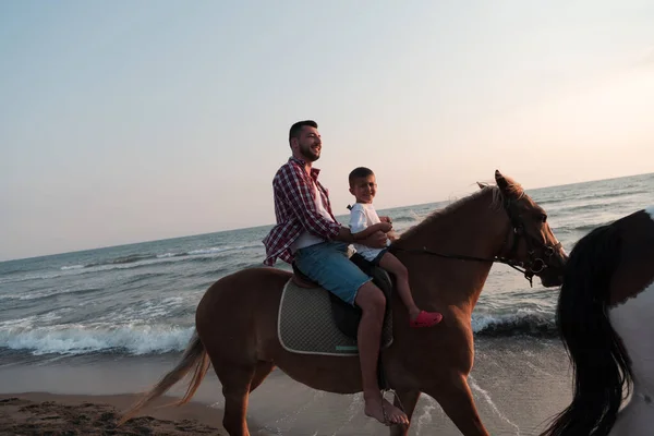 Padre e hijo disfrutan montando caballos juntos junto al mar. Enfoque selectivo —  Fotos de Stock