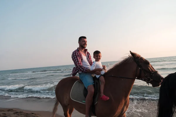 Padre e hijo disfrutan montando caballos juntos junto al mar. Enfoque selectivo —  Fotos de Stock