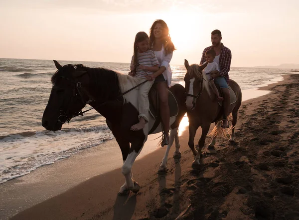 La familia pasa tiempo con sus hijos mientras cabalgan juntos en una playa de arena. Enfoque selectivo — Foto de Stock