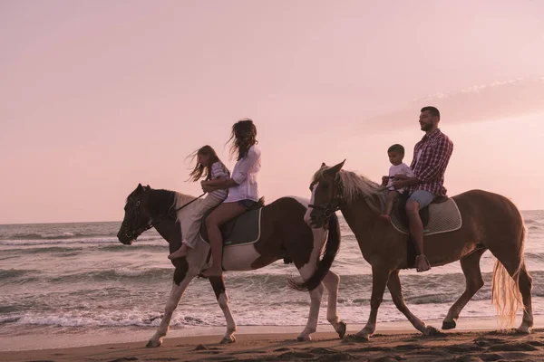 Η οικογένεια περνάει χρόνο με τα παιδιά της ενώ ιππεύει άλογα μαζί σε μια αμμώδη παραλία. Επιλεκτική εστίαση — Φωτογραφία Αρχείου