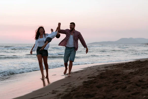 Aile, oğluyla kumsalda yürürken tatilin tadını çıkarıyor. Seçici odak 