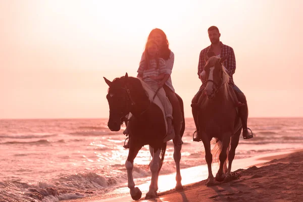 The family spends time with their children while riding horses together on a sandy beach. Selective focus Stock Photo