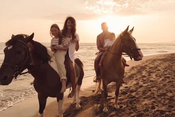 La familia pasa tiempo con sus hijos mientras cabalgan juntos en una hermosa playa de arena al atardecer.. —  Fotos de Stock