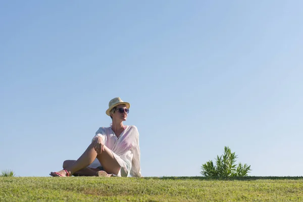 Vrouw ligt en leest haar favoriete boek op een weide bedekt met fris groen gras op een zonnige zomer- of lentedag. — Stockfoto
