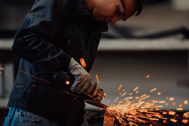 Heavy Industry Engineering Factory Interior with Industrial Worker Using Angle Grinder and Cutting a Metal Tube. Güvenlik Üniforması ve Sert Şapka Üretim Metal Yapıları Müteahhiti. Yüksek kalite