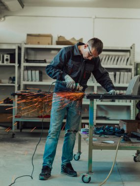Heavy Industry Engineering Factory Interior with Industrial Worker Using Angle Grinder and Cutting a Metal Tube. Güvenlik Üniforması ve Sert Şapka Üretim Metal Yapıları Müteahhiti. Yüksek kalite