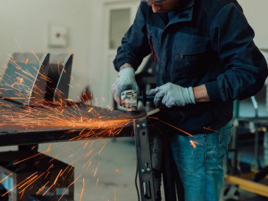 Heavy Industry Engineering Factory Interior with Industrial Worker Using Angle Grinder and Cutting a Metal Tube. Contractor in Safety Uniform and Hard Hat Manufacturing Metal Structures. High-quality