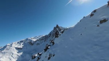 Havadan izleme sporu FPV İHA 'sı dağın tepesine yükseliyor. Alplerin güzel zirveleri kar örtüsüyle kaplıdır. Yüksek kalite 4k görüntü