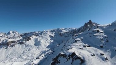 Havadan izleme sporu FPV İHA 'sı dağın tepesine yükseliyor. Alplerin güzel zirveleri kar örtüsüyle kaplıdır. Yüksek kalite 4k görüntü