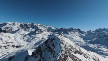 Havadan izleme sporu FPV İHA 'sı dağın tepesine yükseliyor. Alplerin güzel zirveleri kar örtüsüyle kaplıdır. Yüksek kalite 4k görüntü