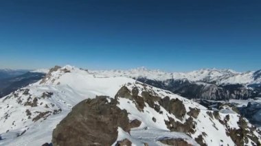 Havadan izleme sporu FPV İHA 'sı dağın tepesine yükseliyor. Alplerin güzel zirveleri kar örtüsüyle kaplıdır. Yüksek kalite 4k görüntü