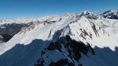Havadan izleme sporu FPV İHA 'sı dağın tepesine yükseliyor. Alplerin güzel zirveleri kar örtüsüyle kaplıdır. Yüksek kalite 4k görüntü