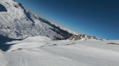 Havadan izleme sporu FPV İHA 'sı dağın tepesine yükseliyor. Alplerin güzel zirveleri kar örtüsüyle kaplıdır. Yüksek kalite 4k görüntü