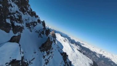 Havadan izleme sporu FPV İHA 'sı dağın tepesine yükseliyor. Alplerin güzel zirveleri kar örtüsüyle kaplıdır. Yüksek kalite 4k görüntü