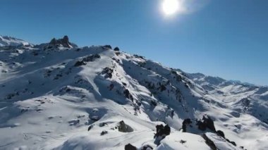 Havadan izleme sporu FPV İHA 'sı dağın tepesine yükseliyor. Alplerin güzel zirveleri kar örtüsüyle kaplıdır. Yüksek kalite 4k görüntü