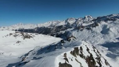 Havadan izleme sporu FPV İHA 'sı dağın tepesine yükseliyor. Alplerin güzel zirveleri kar örtüsüyle kaplıdır. Yüksek kalite 4k görüntü