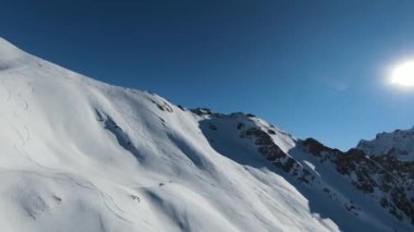 Havadan izleme sporu FPV İHA 'sı dağın tepesine yükseliyor. Alplerin güzel zirveleri kar örtüsüyle kaplıdır. Yüksek kalite 4k görüntü