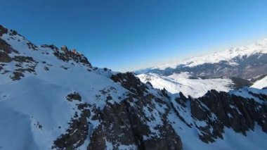 Havadan izleme sporu FPV İHA 'sı dağın tepesine yükseliyor. Alplerin güzel zirveleri kar örtüsüyle kaplıdır. Yüksek kalite 4k görüntü