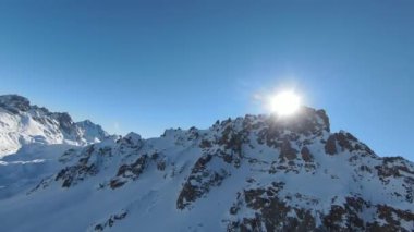 Havadan izleme sporu FPV İHA 'sı dağın tepesine yükseliyor. Alplerin güzel zirveleri kar örtüsüyle kaplıdır. Yüksek kalite 4k görüntü