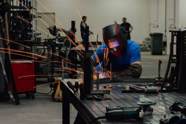 Fabrikanın içinde çalışan profesyonel ağır sanayi kaynakçısı, kask takıyor ve kaynak yapmaya başlıyor. Seçici Odaklanma. Yüksek kaliteli fotoğraf.