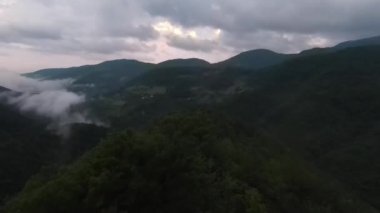 Yağmur mevsiminde yağmur bulutlarıyla dolu yemyeşil tropikal orman dağının üzerinde uçan hava manzaralı Doi Phuka Dağı kuzey Tayland 'daki rezerve edilmiş ulusal park. Yüksek kalite 4k