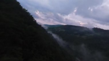 Yağmur mevsiminde yağmur bulutlarıyla dolu yemyeşil tropikal orman dağının üzerinde uçan hava manzaralı Doi Phuka Dağı kuzey Tayland 'daki rezerve edilmiş ulusal park. Yüksek kalite 4k