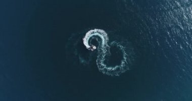 Aerial top view of a white pleasure boat on a summer day. Powerboat turn loop eight on the sea making metaverse infinity future concept. Hi quality 4K footage. 