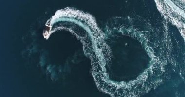 Aerial top view of a white pleasure boat on a summer day. Powerboat turn loop eight on the sea making metaverse infinity future concept. Hi quality 4K footage. 