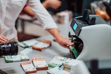 Bank employees using money counting machines while sorting and counting paper banknotes inside a bank vault. Large amounts of money in the bank. High quality photo
