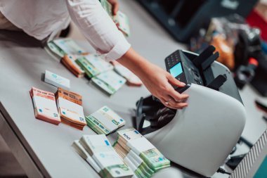 Bank employees using money counting machines while sorting and counting paper banknotes inside a bank vault. Large amounts of money in the bank. High quality photo