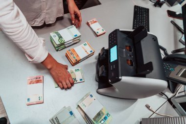 Bank employees using money counting machines while sorting and counting paper banknotes inside a bank vault. Large amounts of money in the bank. High quality photo
