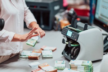 Bank employees using money counting machines while sorting and counting paper banknotes inside a bank vault. Large amounts of money in the bank. High quality photo