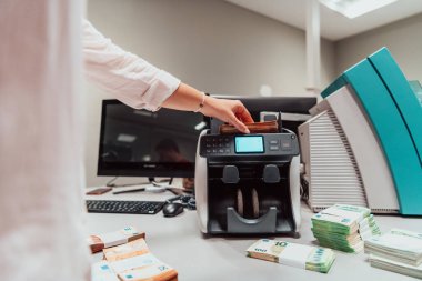 Banka çalışanları bir banka kasasında kağıt banknotları sıralarken ve sayarken para sayma makinelerini kullanıyorlar. Bankada büyük miktarda para var. Yüksek kalite fotoğraf