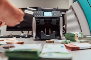 Bank employees using money counting machines while sorting and counting paper banknotes inside a bank vault. Large amounts of money in the bank. High quality photo