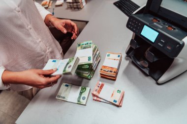 Bank employees using money counting machines while sorting and counting paper banknotes inside a bank vault. Large amounts of money in the bank. High quality photo