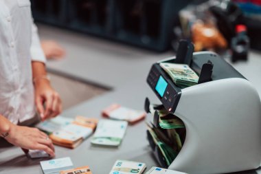 Bank employees using money counting machines while sorting and counting paper banknotes inside a bank vault. Large amounts of money in the bank. High quality photo