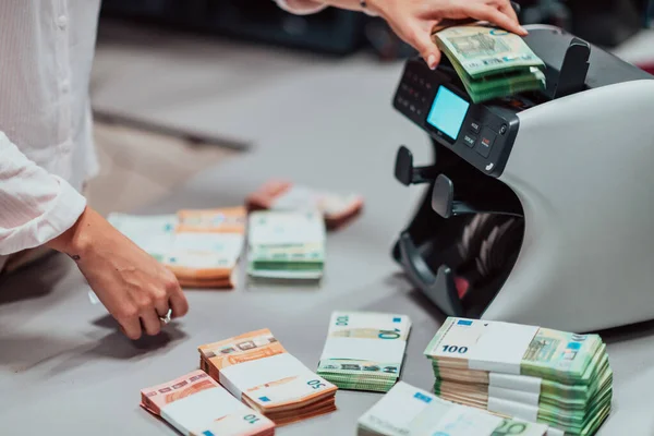 Bank employees using money counting machines while sorting and counting paper banknotes inside a bank vault. Large amounts of money in the bank. High quality photo