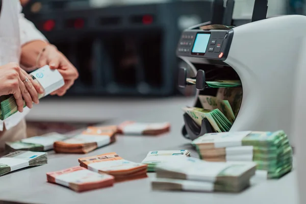 Bank employees using money counting machines while sorting and counting paper banknotes inside a bank vault. Large amounts of money in the bank. High quality photo