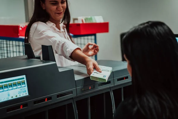 Bank employees using money counting machine while sorting and counting paper banknotes inside bank vault. Large amounts of money in the bank. High quality photo