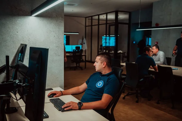 Male security operator working in a data system control room offices Technical Operator Working at workstation with multiple displays, security guard working on multiple monitors Male computer opera