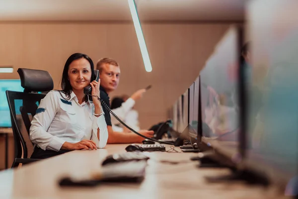 Female security guard operator talking on the phone while working at the workstation with multiple displays Security guards working on multiple monitors. High quality photo