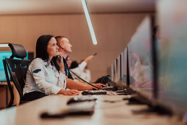 Female security guard operator talking on the phone while working at the workstation with multiple displays Security guards working on multiple monitors. High quality photo