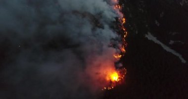 Aerial panoramic view of a forest fire at night, heavy smoke causes air pollution, and fire in full blaze. Natural disaster epic drone cinematic shot. Hi quality 4k footage.