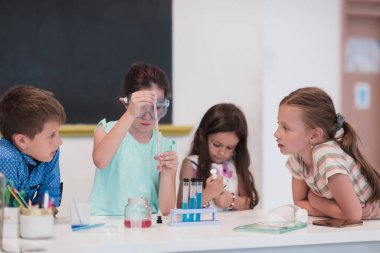 İlköğretim Okulu Bilim Sınıfı: Coşkulu Öğretmen Kimyayı Çeşitli Çocuklar Grubu 'na Açıkladı, Küçük Çocuk Kimyasalları Beakers' a Karıştırdı. Çocuklar ilgiyle öğrenir. Yavaş çekim.